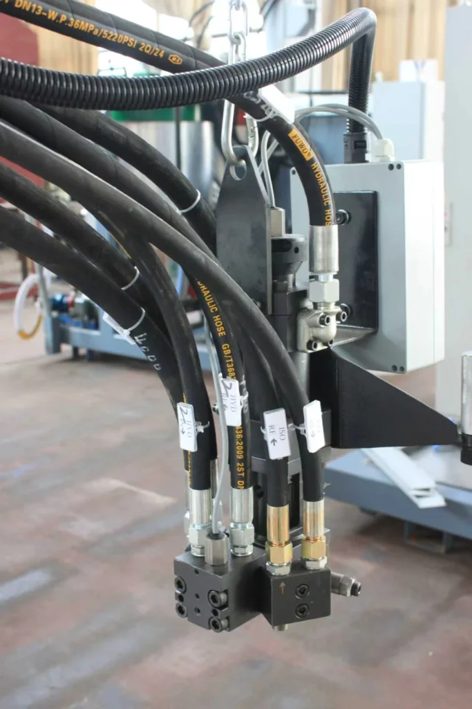 Close-up of a polyurethane mixing head with hydraulic hoses and material line connections