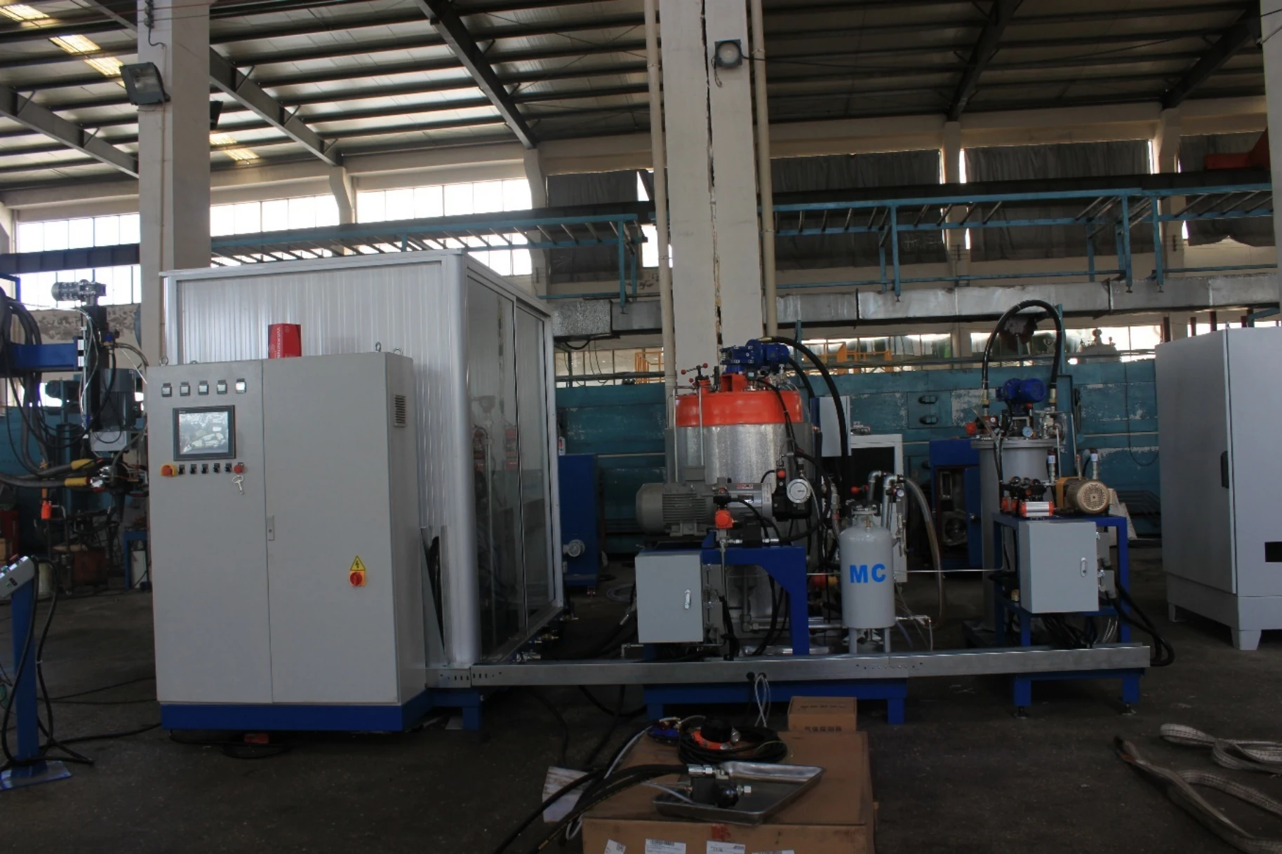 Multi-component high-pressure foaming-system reference showing a control cabinet, material tanks and metering units