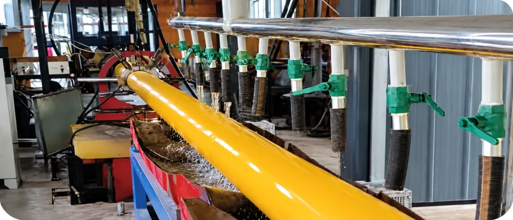 A yellow pipe section beside multiple valves and process lines in a workshop.